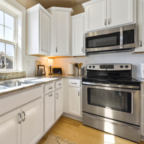 A stainless steel oven and microwave inside a fully furnished kitchen. 